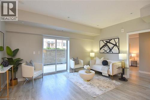 Living area with wood-finish flooring, recessed lighting, and a sliding glass door leading to a patio - 16 Markle Crescent Unit# 111, Ancaster, ON - Indoor Photo Showing Living Room