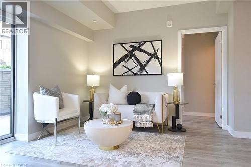 Recessed lighting illuminates this living space featuring light wood-finish flooring, a full-height glass door, and neutral-toned walls - 16 Markle Crescent Unit# 111, Ancaster, ON - Indoor Photo Showing Other Room