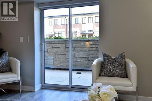 Sliding glass doors opening to an outdoor patio featuring stone wall detailing and paver flooring - 16 Markle Crescent Unit# 111, Ancaster, ON - Indoor Photo Showing Other Room