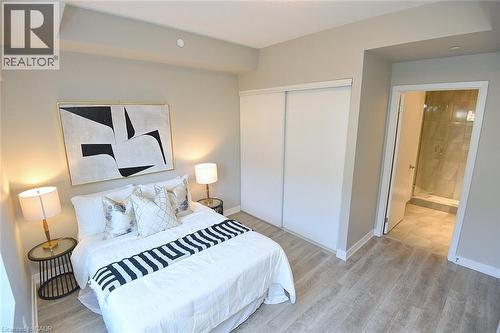 Bedroom featuring light wood-finish flooring, a tray ceiling detail, and a built-in sliding closet - 16 Markle Crescent Unit# 111, Ancaster, ON - Indoor Photo Showing Bedroom