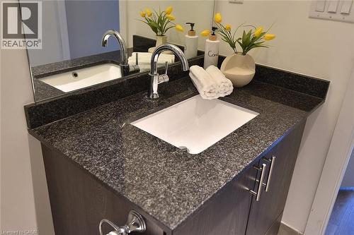 Granite countertop with an undermount sink, chrome faucet, and dark wood-finish cabinetry featuring brushed nickel hardware - 16 Markle Crescent Unit# 111, Ancaster, ON - Indoor Photo Showing Bathroom