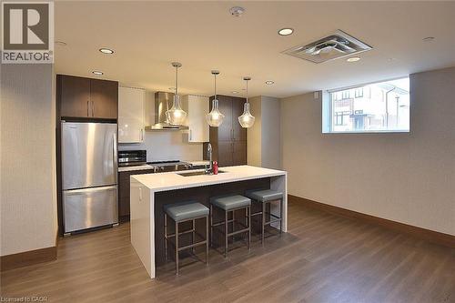 Modern kitchen featuring a waterfall island with counter seating, stainless steel appliances, and mixed-finish cabinetry - 16 Markle Crescent Unit# 111, Ancaster, ON - Indoor Photo Showing Kitchen