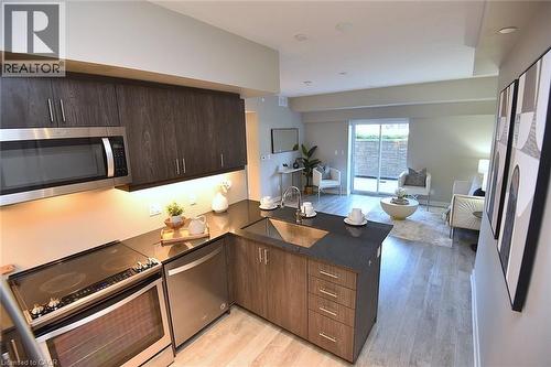 Modern kitchen featuring dark wood-finish cabinetry, stainless steel appliances, and dark countertops - 16 Markle Crescent Unit# 111, Ancaster, ON - Indoor Photo Showing Kitchen