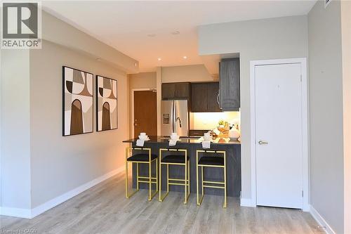 Open-concept kitchen featuring an island with built-in seating, dark cabinetry, stainless steel appliances, and integrated lighting - 16 Markle Crescent Unit# 111, Ancaster, ON - Indoor
