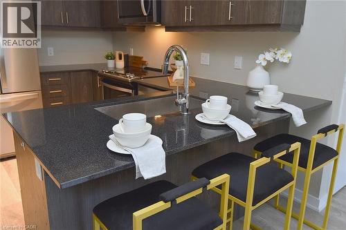 Kitchen island with dark countertop and undermount sink, complemented by matching dark cabinetry - 16 Markle Crescent Unit# 111, Ancaster, ON - Indoor