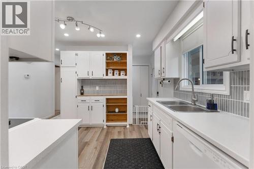 Bright kitchen with white cabinetry, wood-finish flooring, and a subway tile backsplash - 32 Donly Drive N, Simcoe, ON - Indoor Photo Showing Kitchen With Double Sink