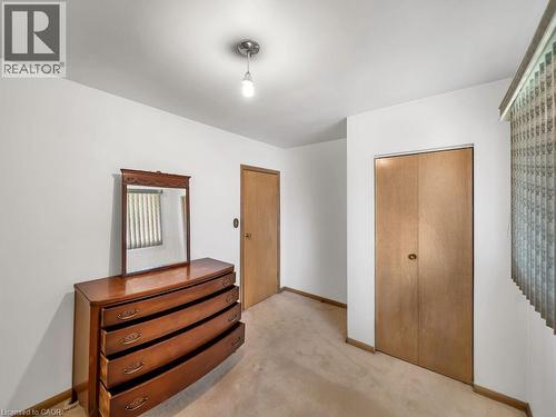 Neutral wall paint with carpet flooring, a flush-mount light fixture, and a wood-finish bi-fold closet door - 1416 Highway 6, Hamilton, ON - Indoor Photo Showing Other Room