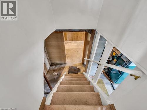 Staircase with carpeted treads and a painted handrail leading to a lower level utility area featuring a boiler and exposed block walls - 1416 Highway 6, Hamilton, ON - Indoor Photo Showing Other Room