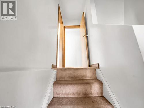 Carpeted staircase with white risers and light-colored walls leading to a doorway with a light wood-finish door and frame - 1416 Highway 6, Hamilton, ON - Indoor Photo Showing Other Room