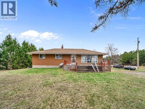 Brick exterior residence featuring a brown shingle roof, a front porch with wood railings, and a gravel driveway - 1416 Highway 6, Hamilton, ON - Outdoor