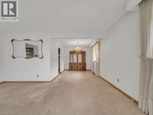 Open-concept living space featuring neutral-toned carpeting, white painted walls, and an ornate gold-framed mirror - 1416 Highway 6, Hamilton, ON - Indoor Photo Showing Other Room
