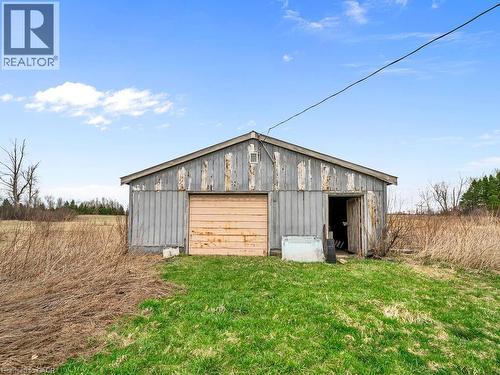 Outbuilding with a peaked roof, wood siding, a roll-up garage door, and a separate side entrance - 1416 Highway 6, Hamilton, ON - Outdoor