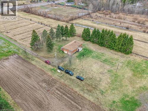 Expansive rural property featuring a brick-sided structure with a brown shingle roof, surrounded by open land and mature trees - 1416 Highway 6, Hamilton, ON - Outdoor With View