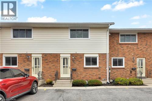 Brick and siding facade townhome featuring white-framed windows, concrete front steps, and a black metal handrail - 32 Montclair Crescent, Simcoe, ON - Outdoor With Exterior