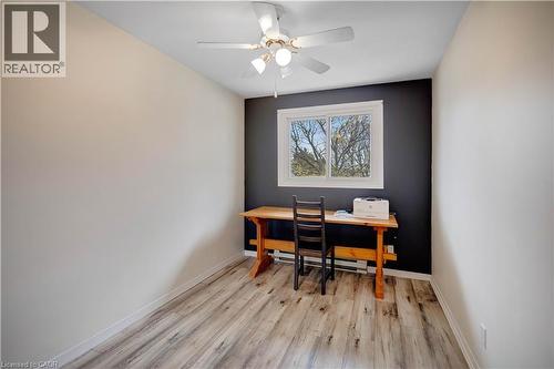 Spacious room featuring wood-finish flooring, a ceiling fan with integrated lighting, and a large window with white trim - 32 Montclair Crescent, Simcoe, ON - Indoor