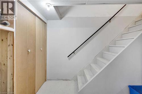 Staircase with white risers and treads, featuring a dark wall-mounted handrail - 32 Montclair Crescent, Simcoe, ON - Indoor Photo Showing Other Room