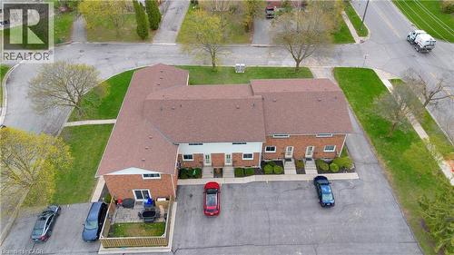 Multi-unit property featuring brick and white siding exteriors, individual front entrances, a shared paved parking area, and private rear patio spaces with fenced perimeters - 32 Montclair Crescent, Simcoe, ON - Outdoor With View