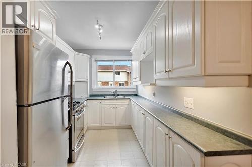 Galley kitchen featuring white cabinetry, stainless steel appliances, dark countertops, a double basin sink, and recessed lighting - 32 Montclair Crescent, Simcoe, ON - Indoor Photo Showing Kitchen With Double Sink