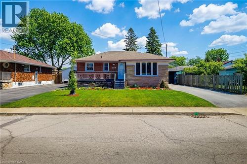 Single-story residence featuring a brick facade with stone accents, a covered front porch with a white railing, and a sloped roof - 103 East 45Th Street, Hamilton, ON - Outdoor