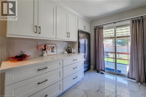 Modern kitchen featuring white shaker-style cabinetry, a stainless steel refrigerator, and sleek countertops - 103 East 45Th Street, Hamilton, ON - Indoor