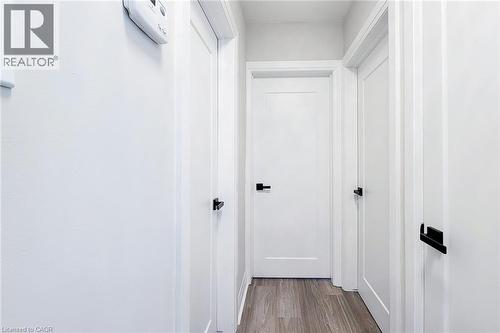 Hallway featuring wood-finish flooring, white paneled doors, and matte black hardware - 103 East 45Th Street, Hamilton, ON - Indoor Photo Showing Other Room