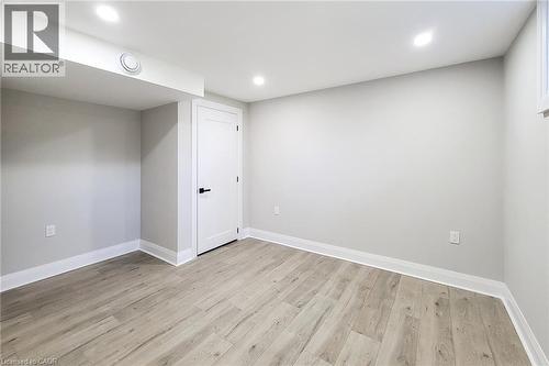 Spacious room featuring light wood-finish flooring, recessed lighting, crisp white trim, and a contemporary white door with matte black hardware - 103 East 45Th Street, Hamilton, ON - Indoor