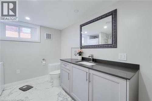 Contemporary bathroom featuring a white vanity with shaker-style cabinetry, a gray solid surface countertop, and a rectangular undermount sink with a chrome faucet - 103 East 45Th Street, Hamilton, ON - Indoor Photo Showing Bathroom