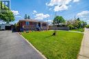 Brick bungalow with a prominent front lawn, an asphalt driveway, and a detached garage structure - 103 East 45Th Street, Hamilton, ON  - Outdoor 