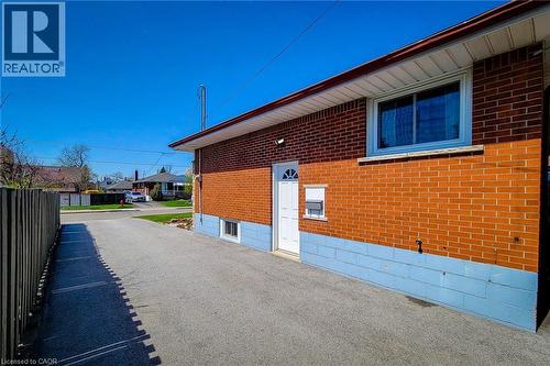 Brick exterior with a white entry door and a single-pane window - 103 East 45Th Street, Hamilton, ON - Outdoor With Exterior