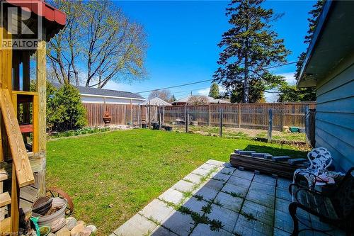 Expansive backyard featuring a green lawn, concrete patio, and perimeter wood fencing - 103 East 45Th Street, Hamilton, ON - Outdoor