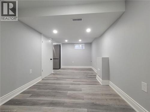 Spacious room featuring light gray walls, wood-finish flooring, recessed ceiling lighting, and white baseboards - 168 Garside Avenue N, Hamilton, ON - Indoor