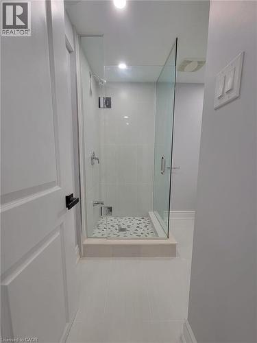 Modern glass-enclosed shower featuring a tiled base with decorative stone accents - 168 Garside Avenue N, Hamilton, ON - Indoor