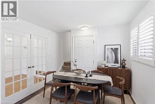 Bright interior with white walls, wood-finish flooring, a white paneled entry door, and a staircase with carpeted treads - 341 Rexford Drive, Hamilton, ON - Indoor Photo Showing Dining Room