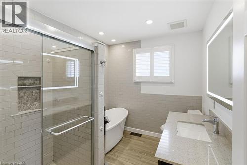 Modern bathroom featuring a glass-enclosed shower with subway tile, a freestanding soaking tub, and a vanity with a stone-finish countertop - 341 Rexford Drive, Hamilton, ON - Indoor Photo Showing Bathroom