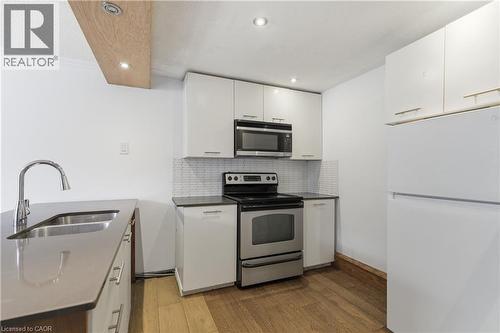 Contemporary kitchen featuring white cabinetry, stainless steel appliances, and wood-finish flooring - 341 Rexford Drive, Hamilton, ON - Indoor Photo Showing Kitchen With Stainless Steel Kitchen With Double Sink With Upgraded Kitchen