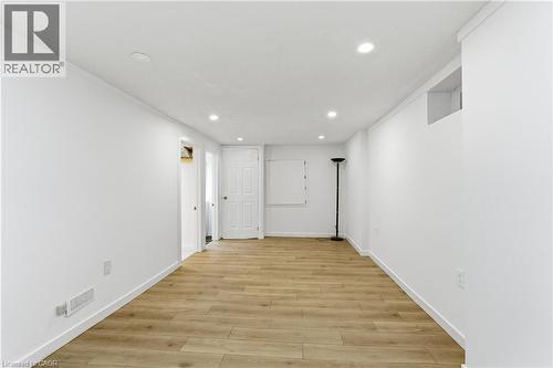 Spacious room featuring light wood-finish flooring, recessed lighting, white baseboards, and bright white walls - 341 Rexford Drive, Hamilton, ON - Indoor Photo Showing Other Room
