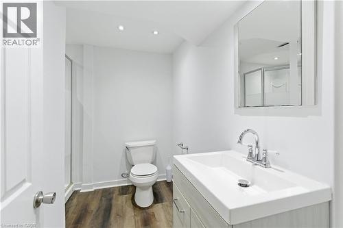 Modern bathroom featuring a single vanity with an integrated sink, wood-finish flooring, a glass-enclosed shower, recessed lighting, and a mirrored medicine cabinet - 341 Rexford Drive, Hamilton, ON - Indoor Photo Showing Bathroom