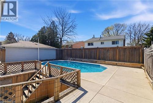 Private backyard oasis featuring an in-ground pool, concrete patio, and a multi-level wood deck with lattice railings - 341 Rexford Drive, Hamilton, ON - Outdoor
