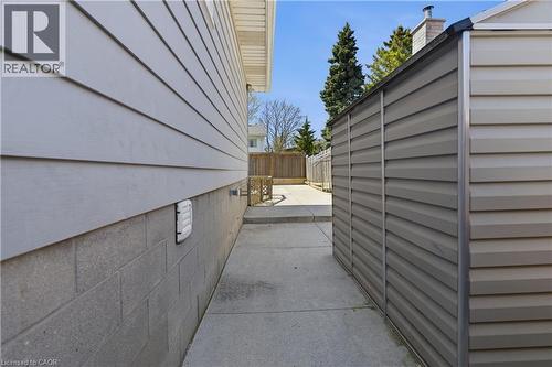 Concrete pathway between the property's light gray siding and a tan-paneled storage shed - 341 Rexford Drive, Hamilton, ON - Outdoor With Exterior