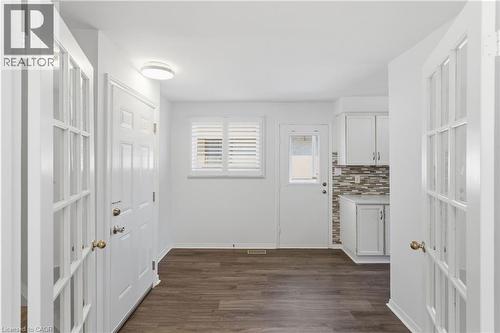 Entry area featuring wood-finish flooring, white paneled doors, and a decorative frosted glass door - 341 Rexford Drive, Hamilton, ON - Indoor Photo Showing Other Room