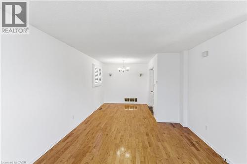 Spacious interior featuring wood-finish flooring, white walls, and a window with plantation shutters - 341 Rexford Drive, Hamilton, ON - Indoor Photo Showing Other Room