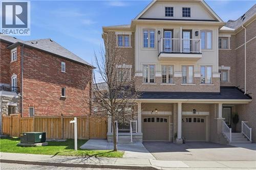 Multi-story townhouse with a brick and stucco facade, featuring two integrated garage doors with arched window inserts, and an upper-level balcony with white railings - 9 Rabbit Run Way, Brampton, ON - Outdoor With Facade