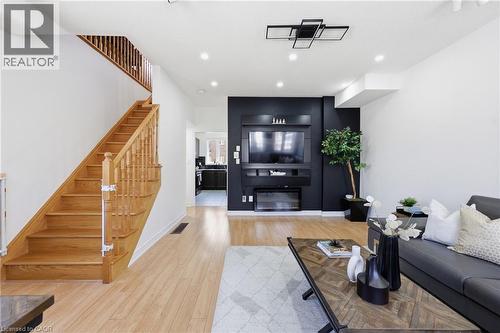 Open-concept living space featuring wood-finish flooring, a contemporary ceiling light fixture, recessed lighting, and a built-in media console with an integrated fireplace - 9 Rabbit Run Way, Brampton, ON - Indoor Photo Showing Living Room