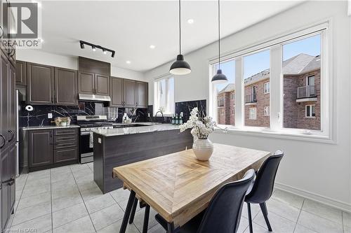 Contemporary kitchen featuring dark wood-finish cabinetry, black marble-style backsplash, and light tile flooring - 9 Rabbit Run Way, Brampton, ON - Indoor