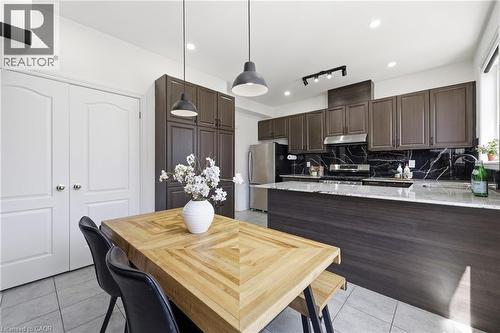 Modern kitchen with dark wood-finish cabinetry, stainless steel appliances, and a granite-look countertop island - 9 Rabbit Run Way, Brampton, ON - Indoor