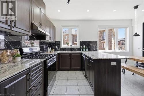 Contemporary kitchen featuring granite countertops, wood-finish cabinetry, a gas range, and a black marble-effect backsplash - 9 Rabbit Run Way, Brampton, ON - Indoor Photo Showing Kitchen With Upgraded Kitchen