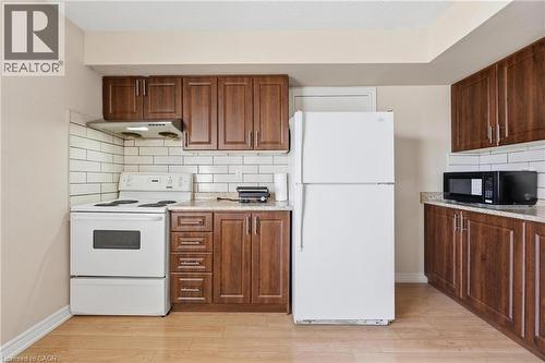 Kitchen featuring wood-finish cabinetry, white subway tile backsplash, white appliances, and light-toned countertops - 9 Rabbit Run Way, Brampton, ON - Indoor Photo Showing Kitchen