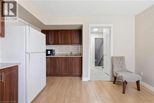 Kitchenette featuring wood-finish flooring, dark wood cabinetry, white subway tile backsplash, and light-toned countertops - 9 Rabbit Run Way, Brampton, ON - Indoor