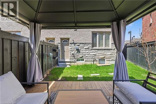 Covered outdoor living space featuring a wood-finish deck, dark-stained privacy fence, and a grassed yard area - 9 Rabbit Run Way, Brampton, ON - Outdoor With Exterior
