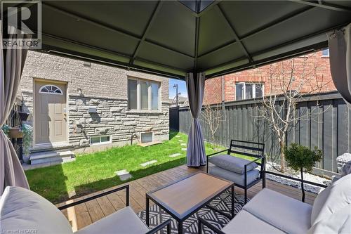 Covered outdoor deck with wood-finish flooring, featuring a dark metal gazebo frame and privacy curtains - 9 Rabbit Run Way, Brampton, ON - Outdoor With Deck Patio Veranda With Exterior